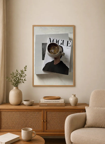 Portrait poster featuring a person’s face obscured by a coffee mug atop stacked Vogue magazine pages, monochrome with beige accents