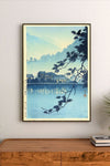 Portrait print featuring tranquil blue-toned landscape with silhouetted branches, distant illuminated Japanese buildings, and reflective water