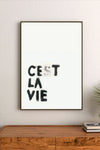 Portrait wall art print featuring minimalist black text on a neutral backdrop, displayed in a modern room setting with light walls