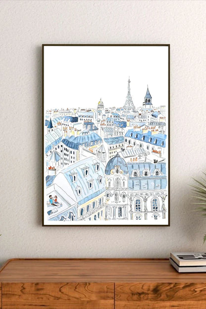 Framed artwork of a cityscape with blue and white buildings on a wall above a wooden cabinet.