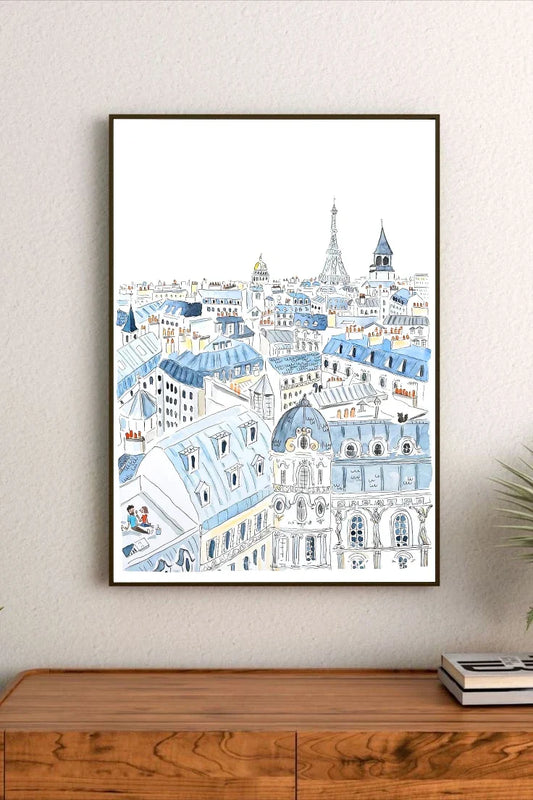 Framed artwork of a cityscape with blue and white buildings on a wall above a wooden cabinet.