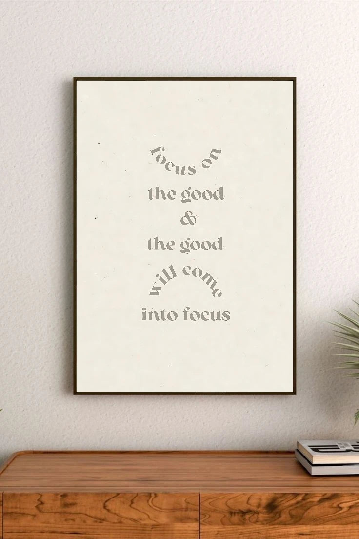 Portrait poster with minimalist typography in muted grey on off-white background, reading "focus on the good & the good will come into focus"
