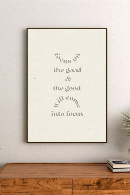 Portrait poster with minimalist typography in muted grey on off-white background, reading "focus on the good & the good will come into focus"